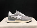 Outer side profile of a grey sneaker showing the white star emblem, BAPE detail near the heel, and black outsole.