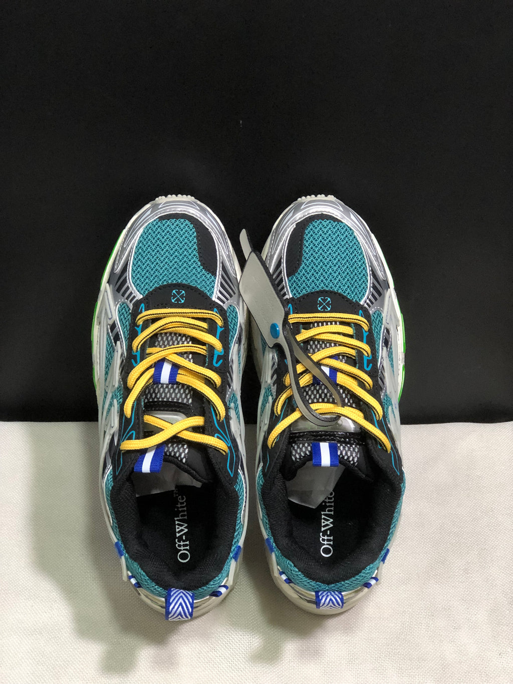 Top view showing teal mesh toe boxes, yellow laces, blue accents, and black padded collars.