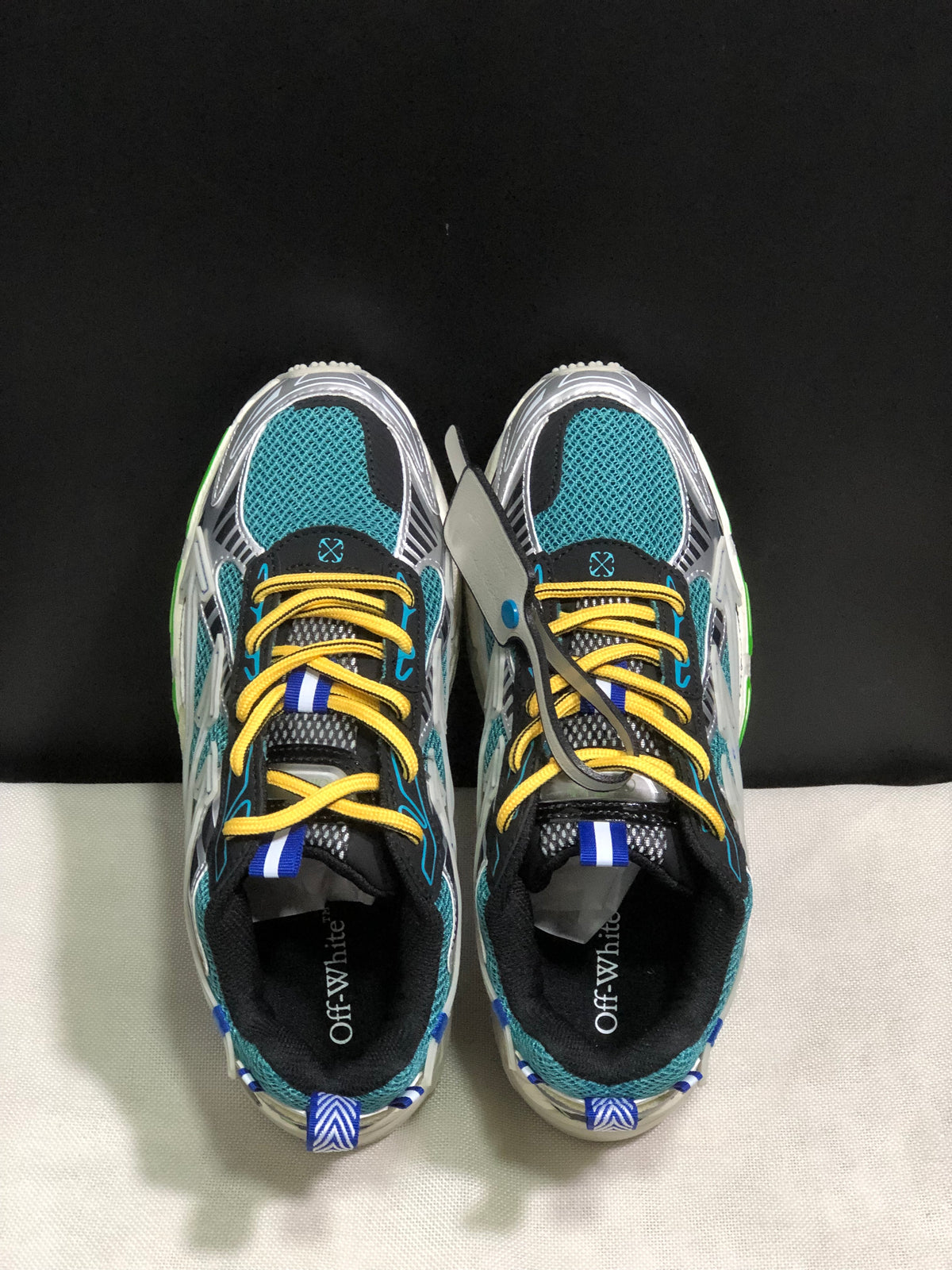Top view showing teal mesh toe boxes, yellow laces, blue accents, and black padded collars.