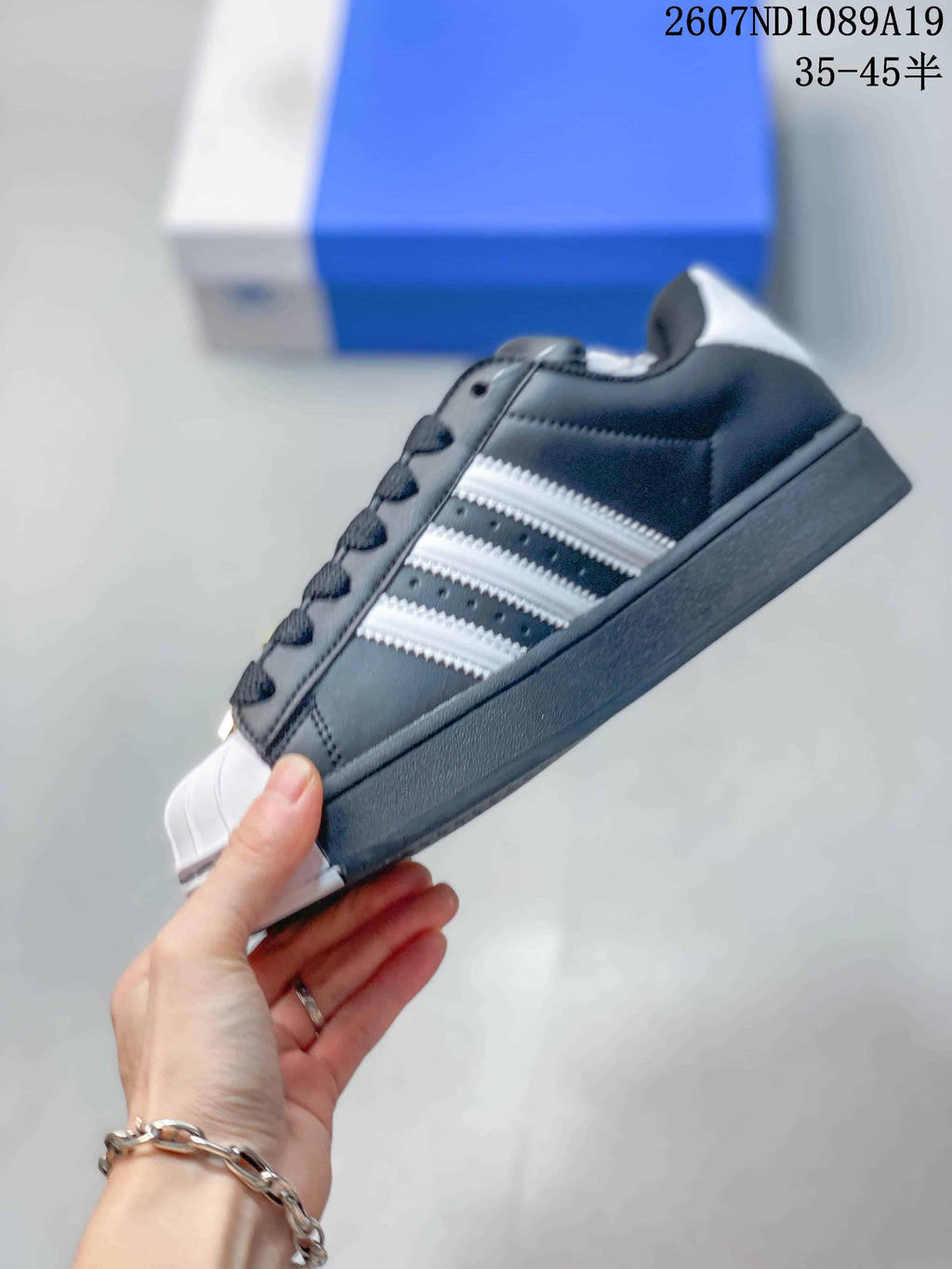Side view of the black sneaker showing white serrated three-stripe detailing, shell toe and flat sole.