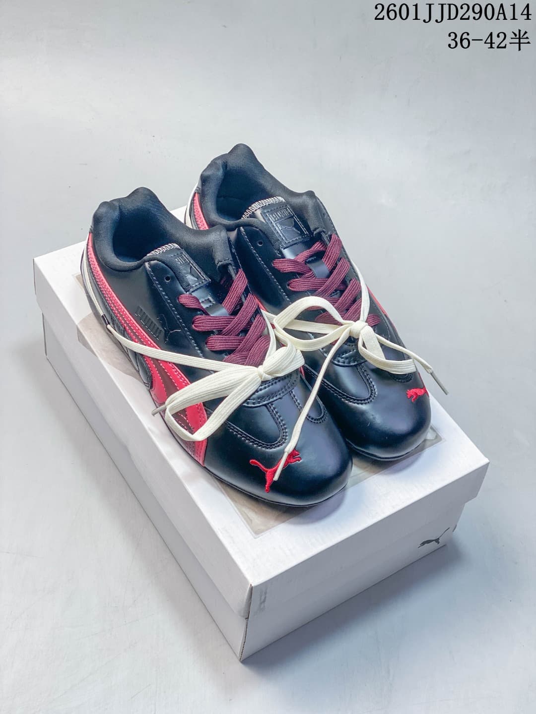 Pair of black and red PUMA Speedcat TTF sneakers displayed on a shoebox, with contrasting white laces; image text shows style code 2601JJD290A14 and size range 36–42.