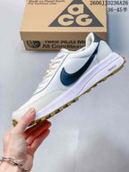 Side profile of a white Nike ACG sneaker with dark side detailing, white midsole, and gum-colored lugged outsole.