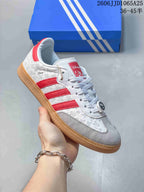 Angled side view showing the white and red upper, embossed Disney-themed pattern, soccer-ball ornament, and gum outsole.