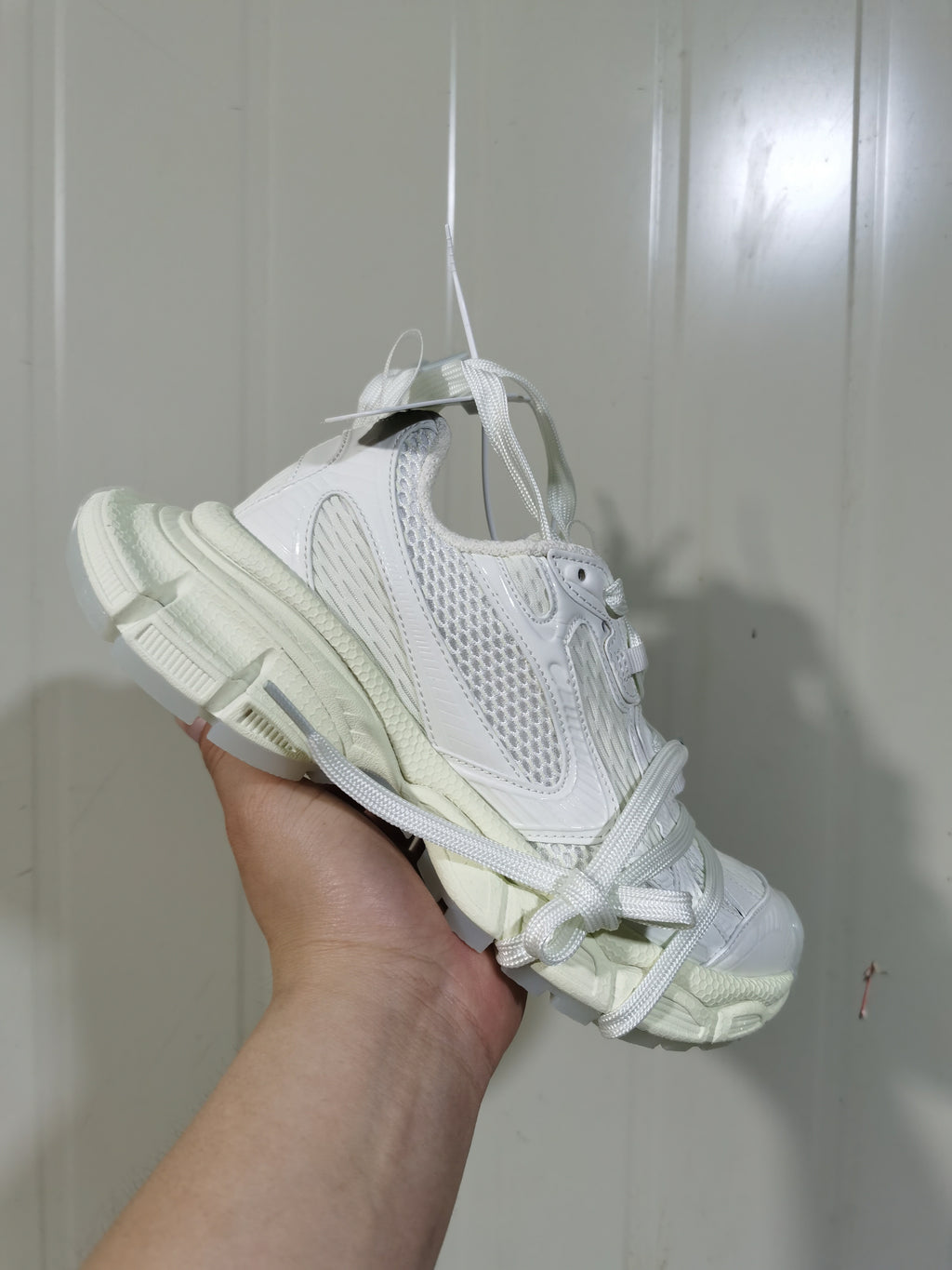 Angled front view of a white mesh sneaker with long flat laces and a chunky outsole.