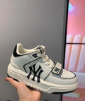 White and black MLB sneaker with a New York side logo, front strap, laces, padded collar, and layered rubber outsole.