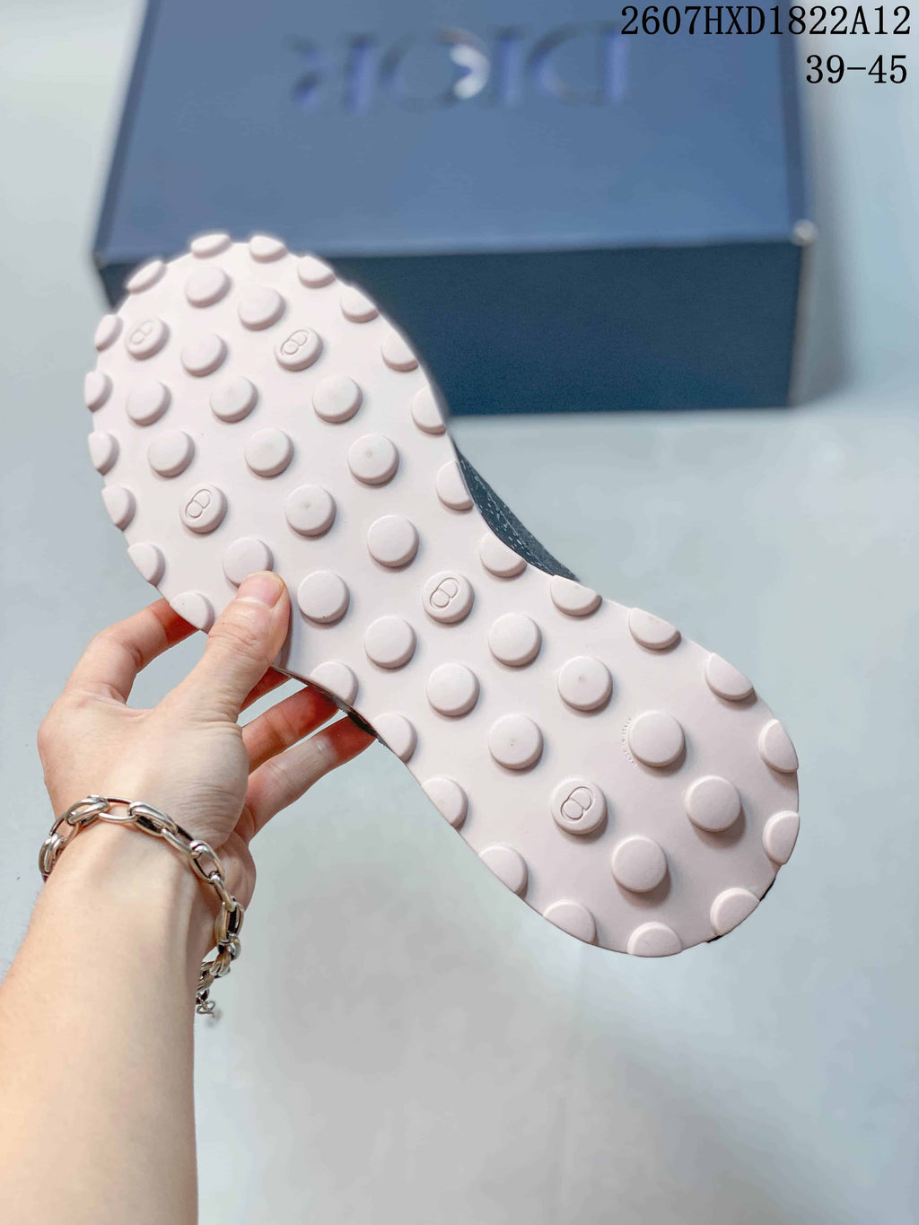 Close view of the light pink outsole with raised circular traction elements and Dior branding.