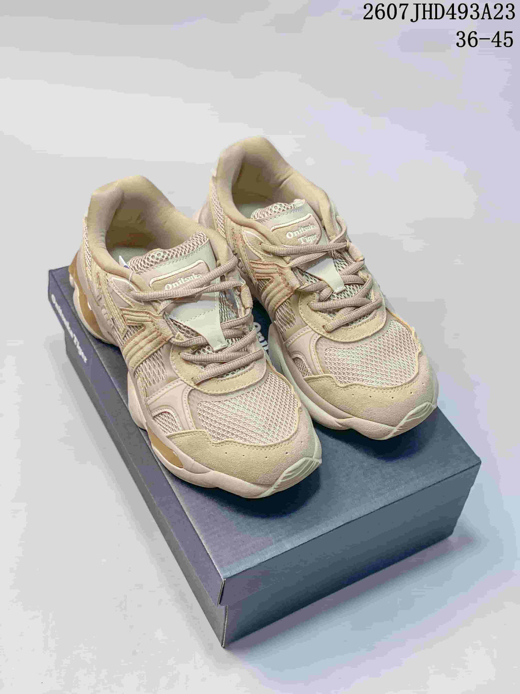 Pair of beige and cream Onitsuka Tiger TIGRUN sneakers displayed on a shoe box, with the source-listed code and size range visible above.