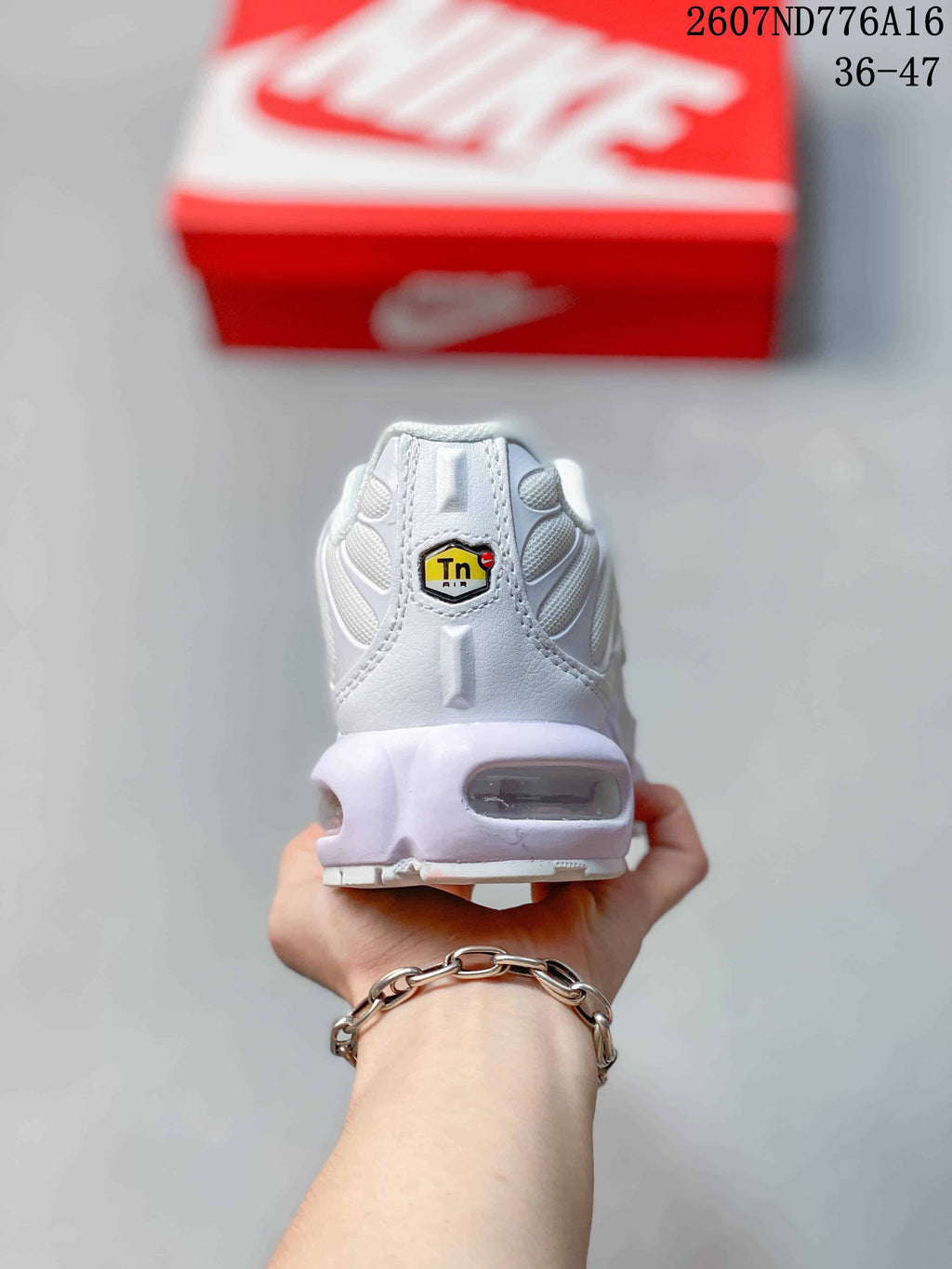 Rear view of a white Nike Air Max Plus sneaker showing the heel branding detail and visible heel Air unit; style code 2607ND776A16 and size range 36–47 are overlaid.