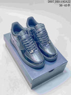 Pair of black Nike low-top sneakers displayed on a shoebox, showing perforated toe boxes, lace-up fronts and swoosh panels.