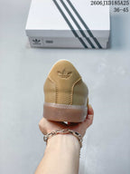 Rear view of the tan sneaker showing the embossed trefoil logo and translucent outsole.