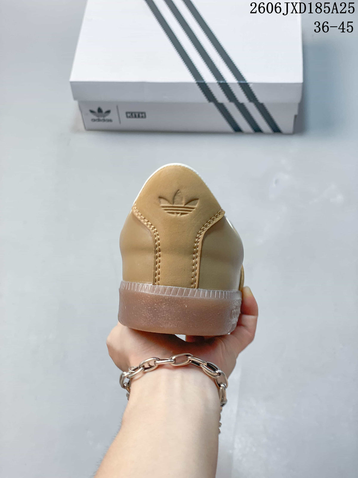 Rear view of the tan sneaker showing the embossed trefoil logo and translucent outsole.