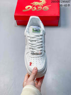 Top view of a white sneaker showing the perforated toe box, white laces, and embroidered red detail.