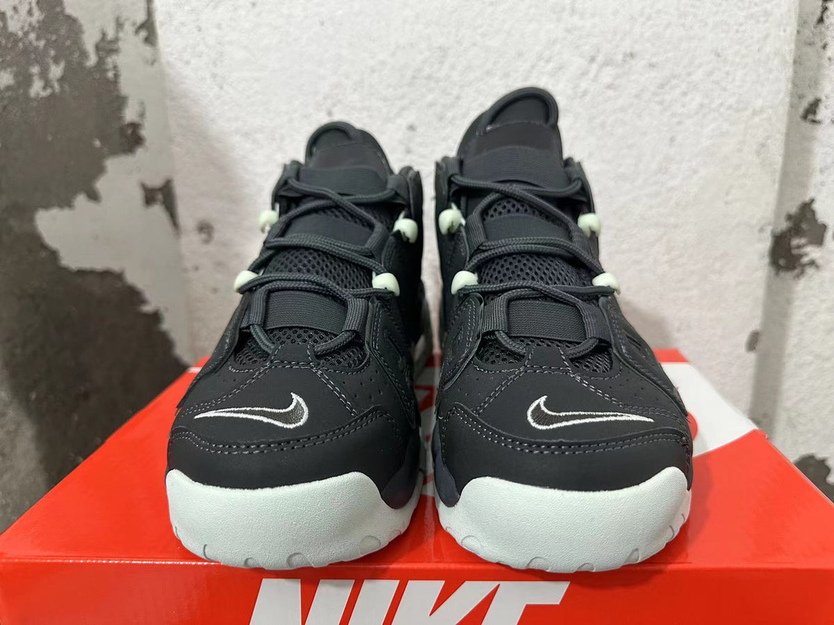 Front view of black Nike sneakers with white toe outsoles, small outlined Swooshes, and pale mint-green lace details.
