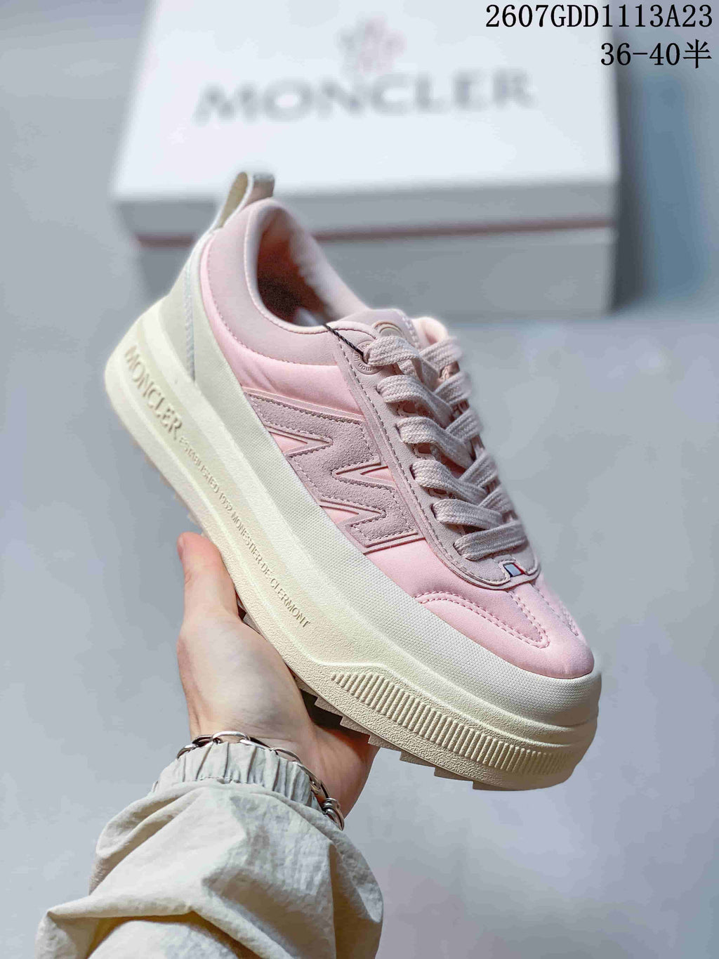 Side view of a pink Moncler Pacey sneaker showing the layered upper, padded collar, lace-up front, and raised sole.