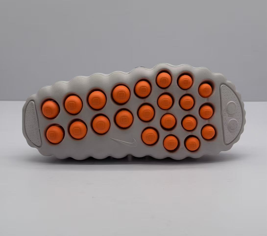 Bottom view showing the light-colored outsole with multiple orange circular traction elements and Nike branding.