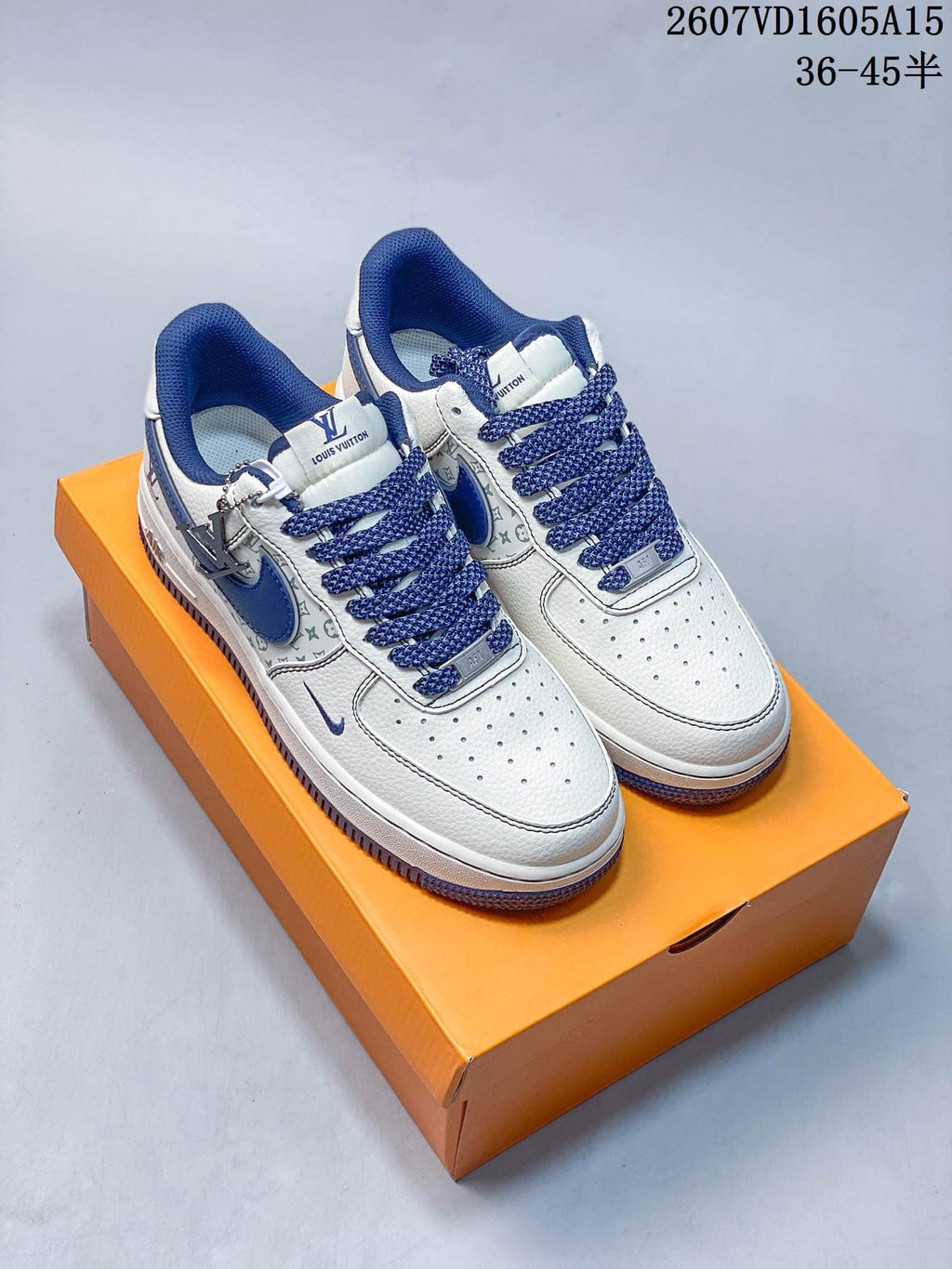Pair of white and blue low-top sneakers with patterned side panels, blue laces, decorative branding, and an orange shoebox.