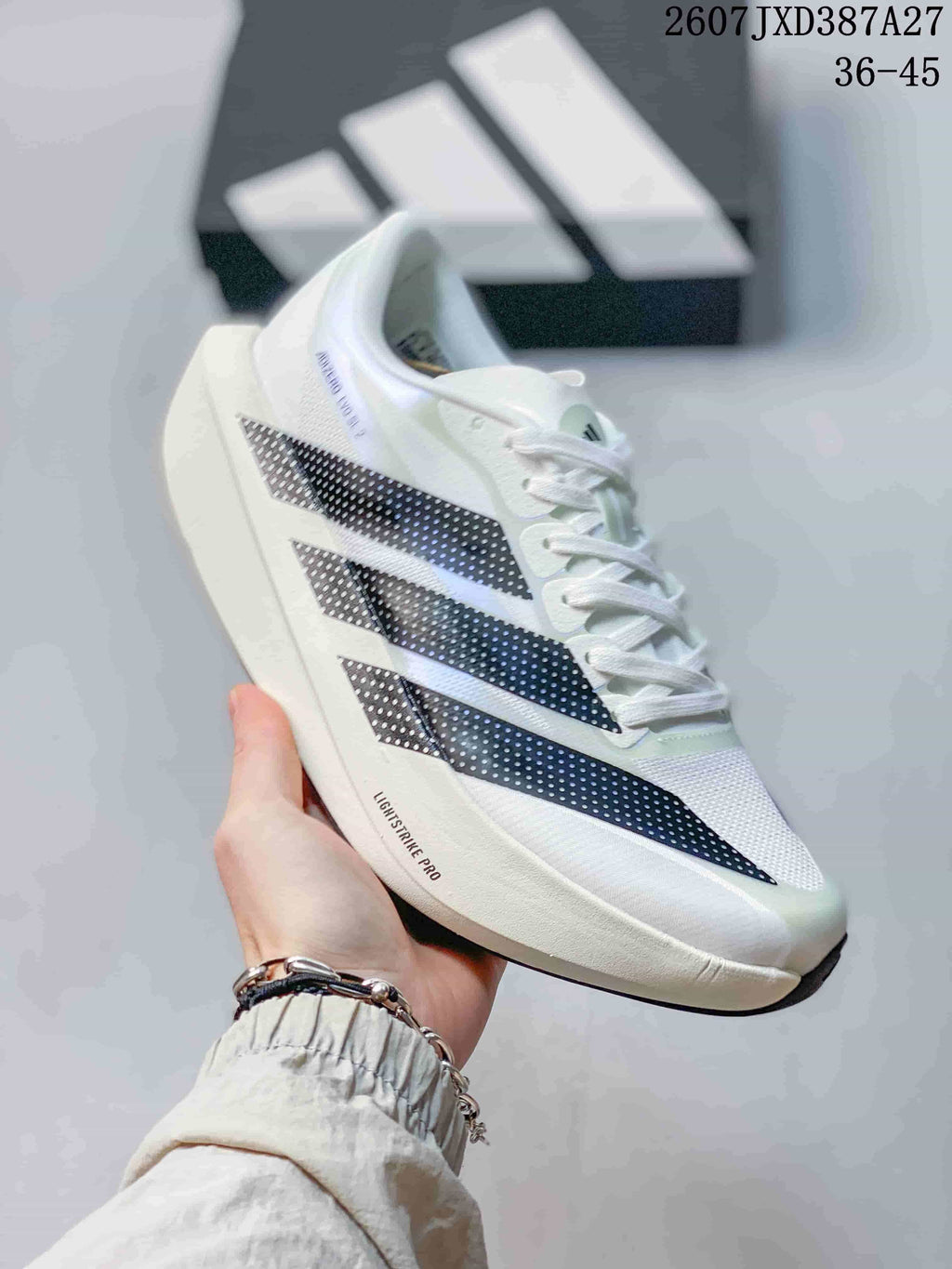 Angled side view of the white adidas sneaker with black patterned stripes and visible Lightstrike Pro branding.