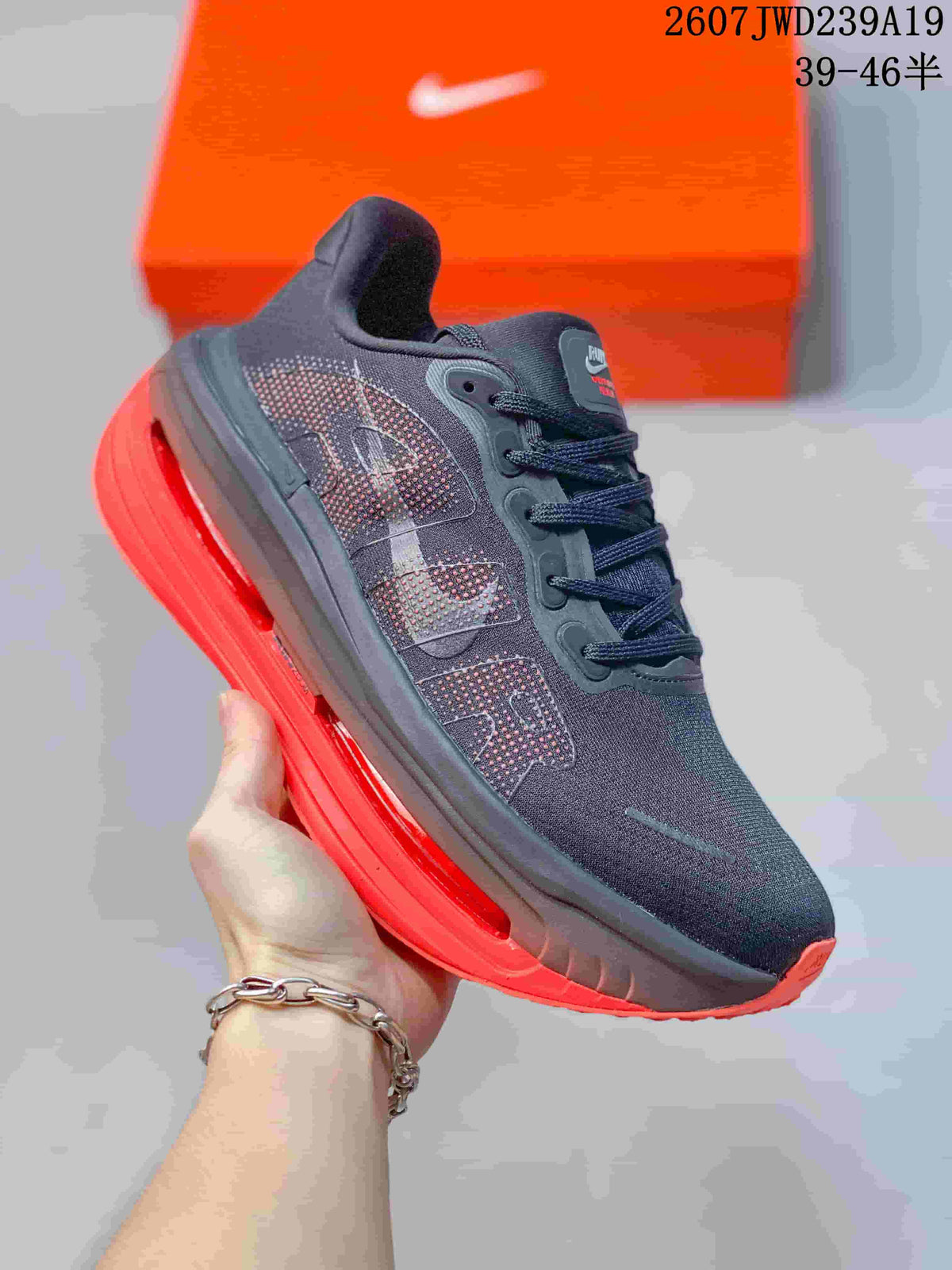 Angled side view of one dark sneaker with mesh panels, side overlays, and red outsole detailing.