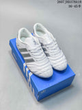 White adidas low-top sneakers with dark side stripes, laces and quilted toe detailing displayed on a blue shoebox.
