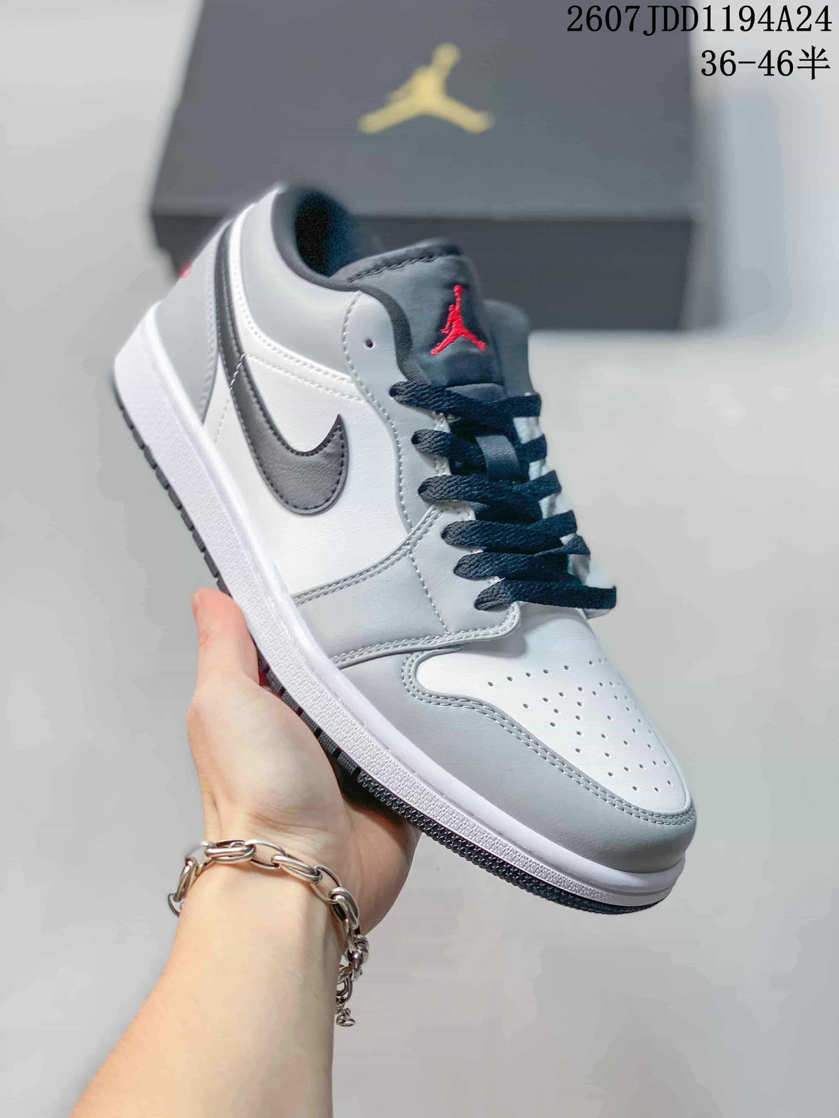 White and grey low-top Jordan sneaker shown from a front three-quarter angle, with a red tongue logo and dark laces.
