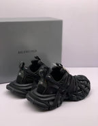 Angled rear-side view of the black sneakers showing heel details and layered laces.