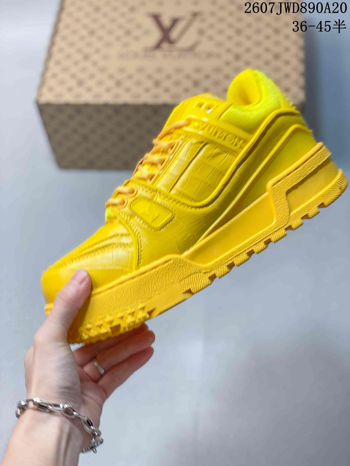 Side view of the yellow low-top sneaker showing layered panels, lace-up construction and a thick treaded outsole.