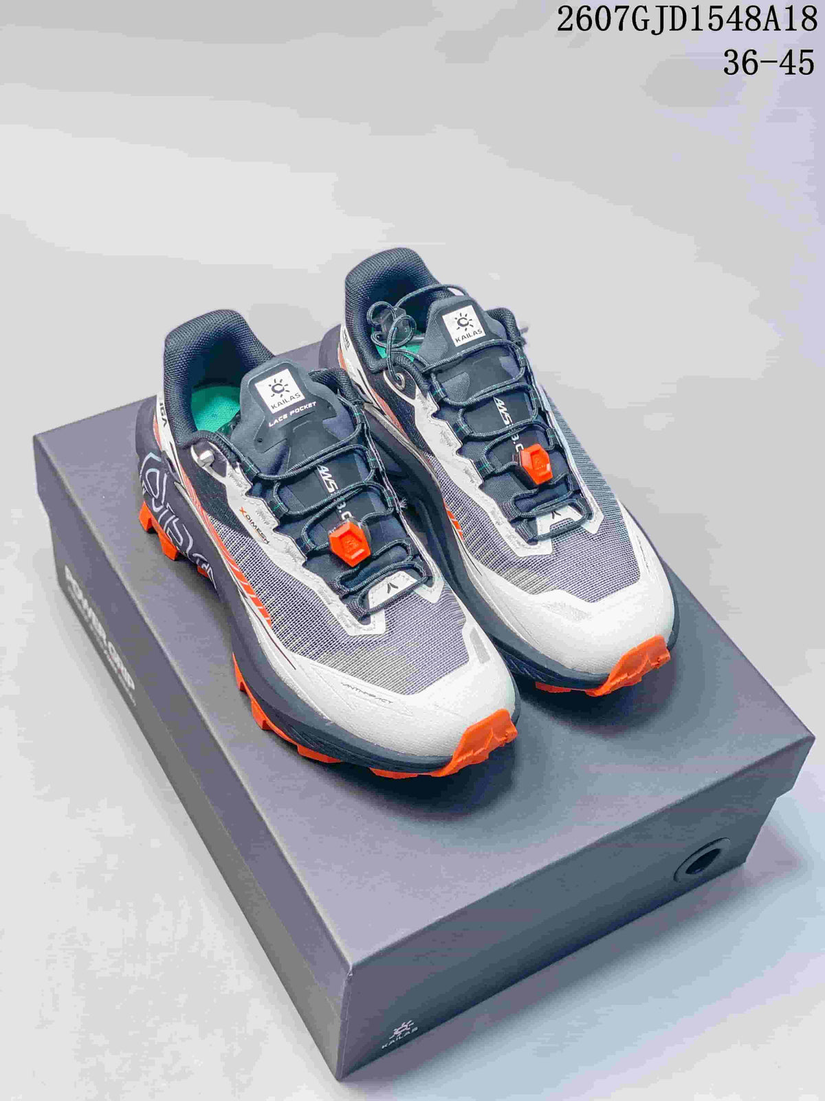 Pair of KAILAS FUGA trail running shoes in gray, white, black, and orange displayed on a shoebox; style code 2607GJD1548A18 and size range 36–45 are visible.