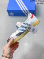 Side view of the sneaker showing the blue stripes, red heel accent, hook-and-loop strap, and attached product tag.