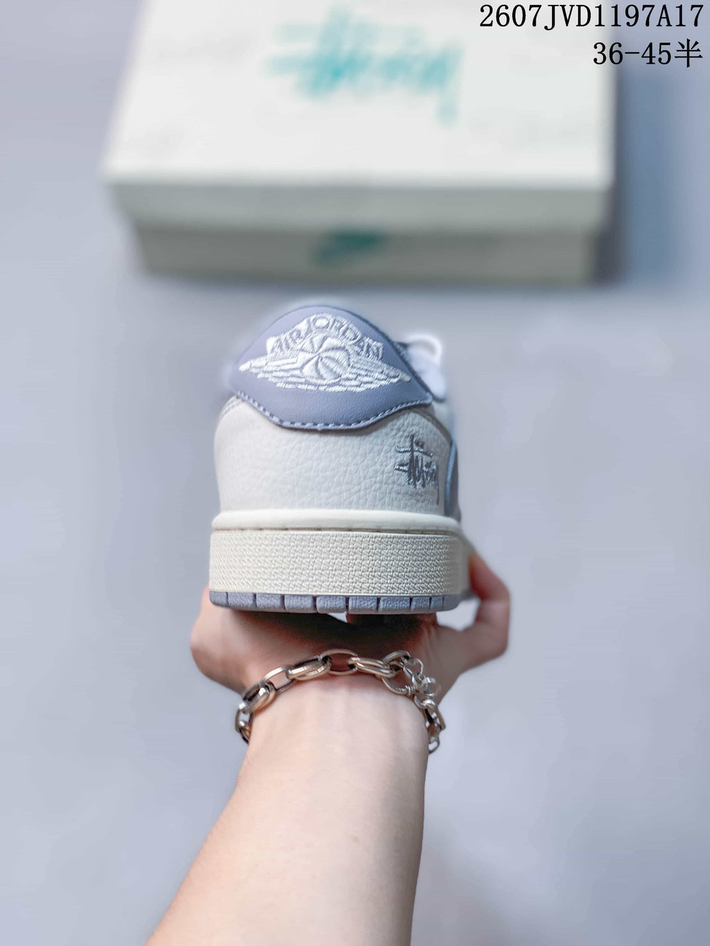 Rear view showing the grey heel panel, embroidered branding, white upper, and layered outsole.