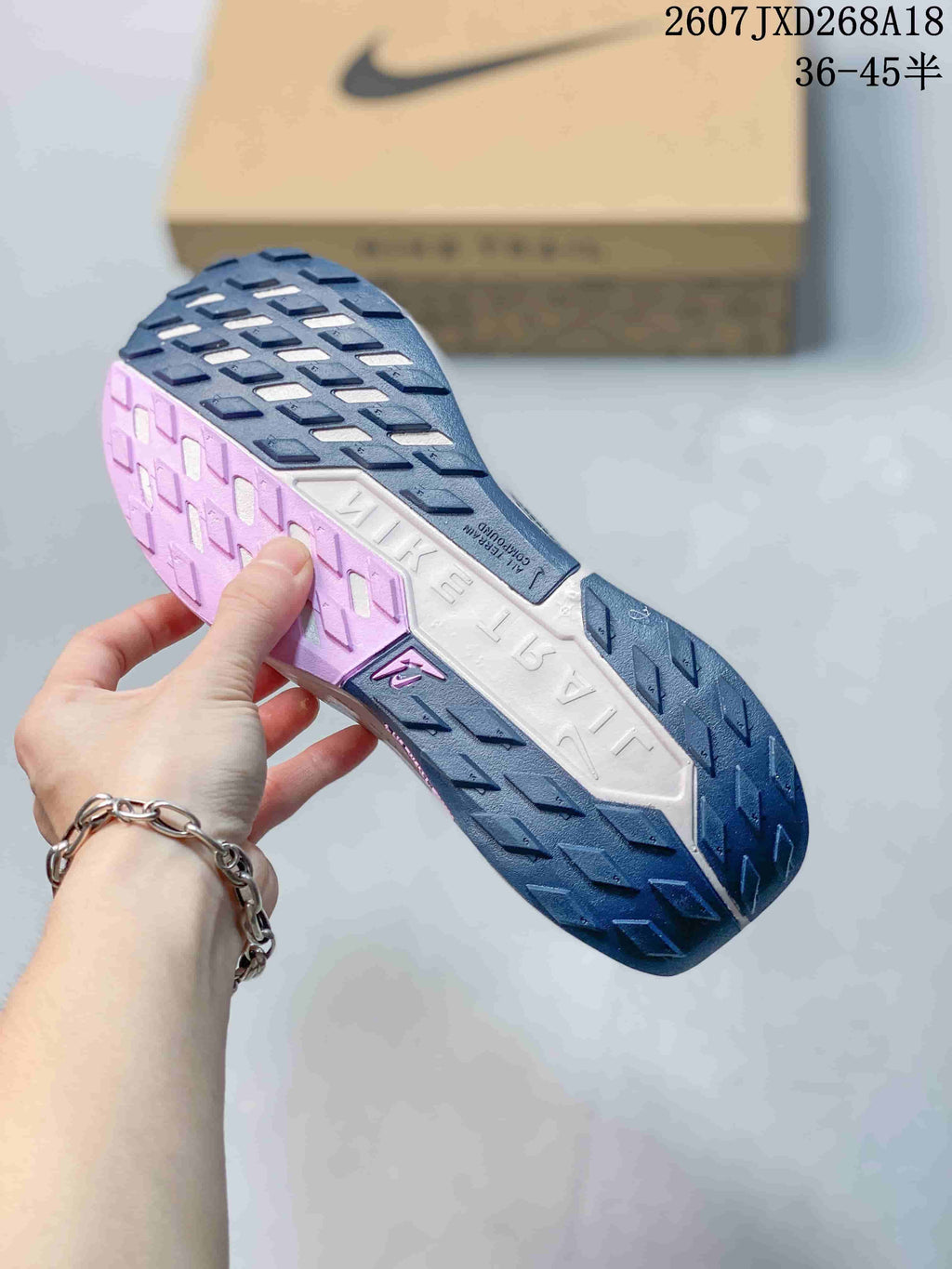 Underside view of the blue sneaker showing the segmented patterned outsole and contrasting pink and white midsole sections.