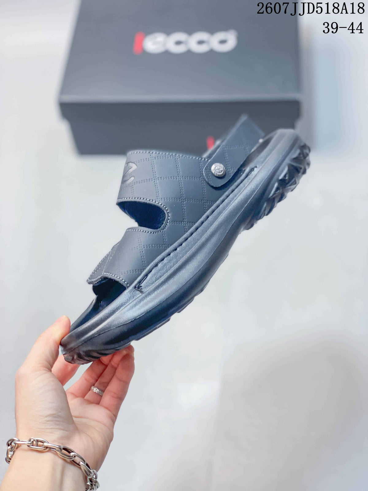 Side view of the black sandal showing the layered sole, heel strap and adjustable upper.