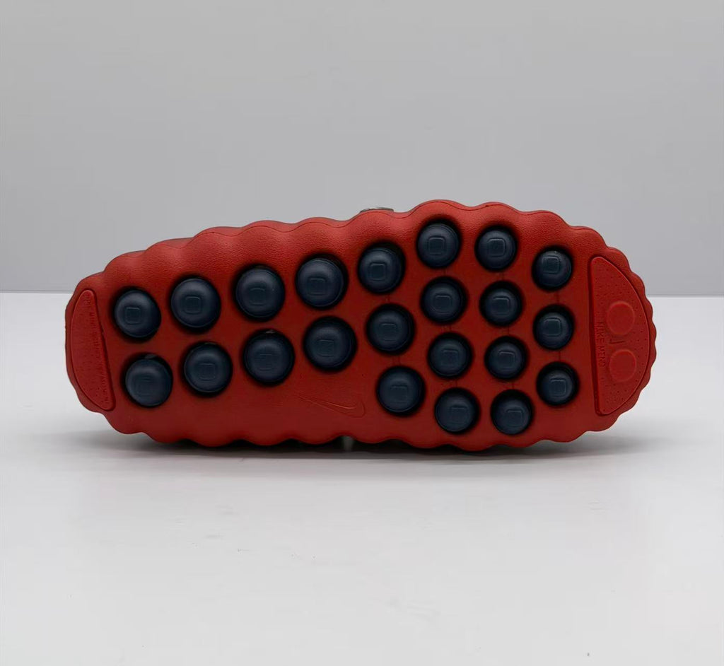 Bottom view showing the dark red outsole with multiple black circular traction elements.