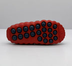 Bottom view showing the dark red outsole with multiple black circular traction elements.