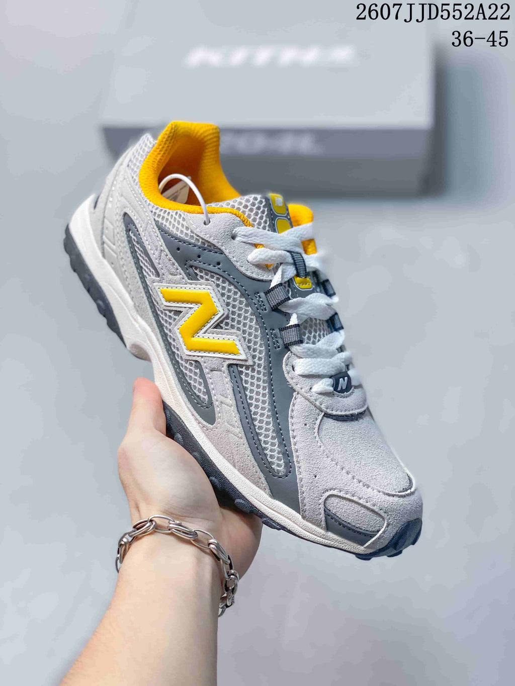 Angled side view of one grey and yellow New Balance NB204 sneaker with its lace-up construction.