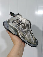 Close-up view of taupe and metallic silver New Balance 2000 runner-style sneaker with dark laces and layered panels.