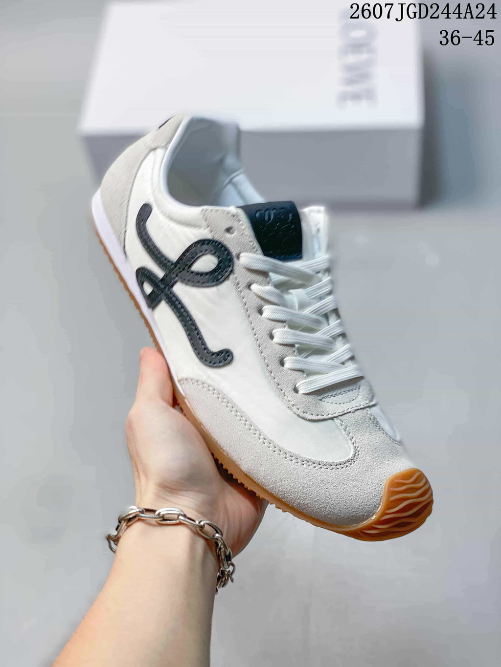 Angled view of the white low-top sneaker showing the black side detail, lace-up construction and gum outsole.