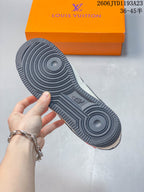 Underside of a cream and charcoal low-top sneaker showing the dark patterned outsole