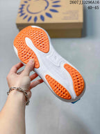 Underside view of a blue, white, and orange running shoe showing the textured orange outsole sections.
