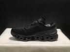 Side profile of a single black sneaker showing its padded collar, side branding and outsole structure.