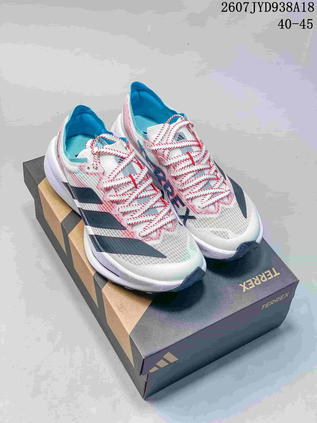 Pair of white Adidas running shoes with pink, blue, and black accents displayed on a shoebox; size range text 40–45 is visible.