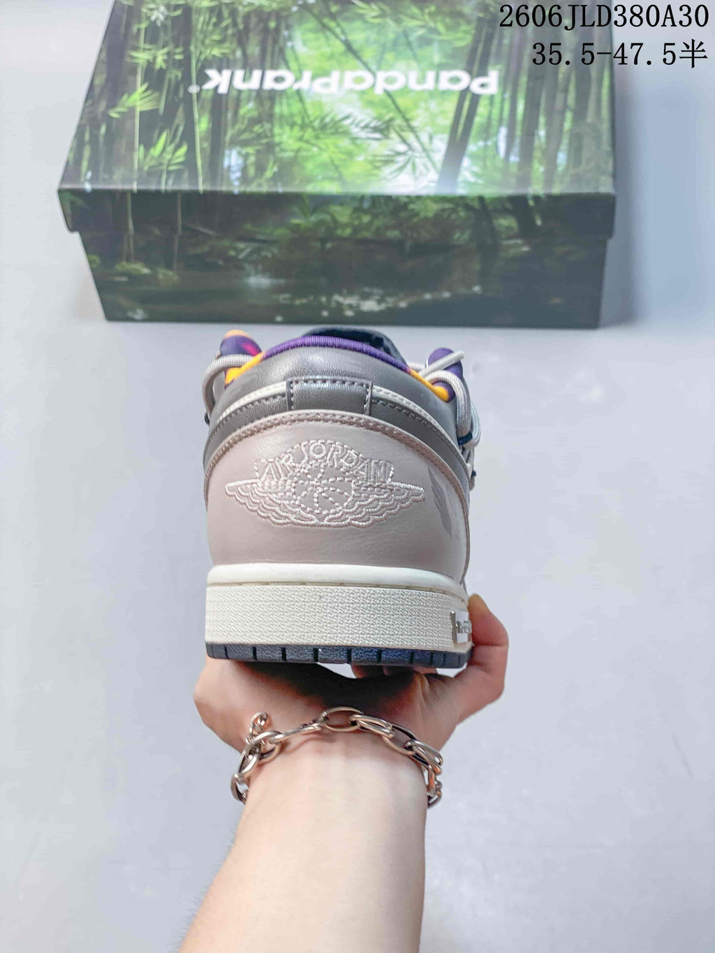 Rear view of a pink and gray low-top sneaker with embroidered wing-style branding.