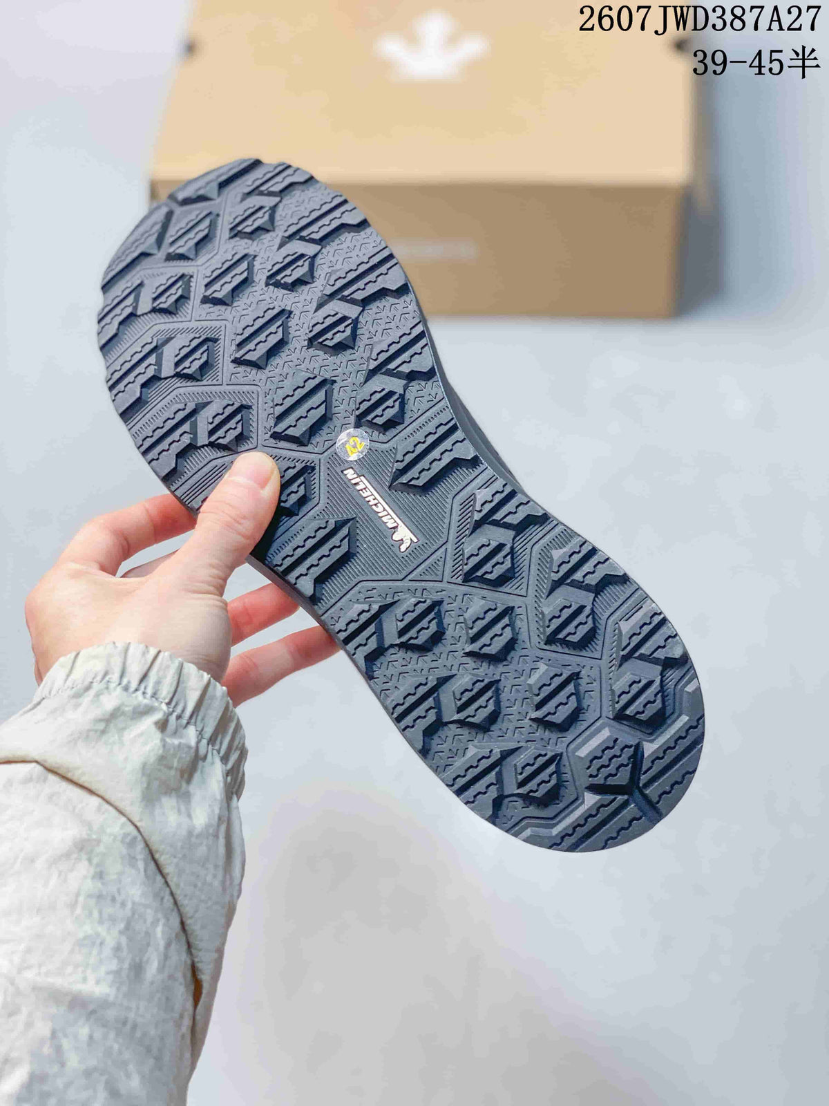 Close view of the patterned outsole with deep geometric traction grooves and DESCENTE branding.