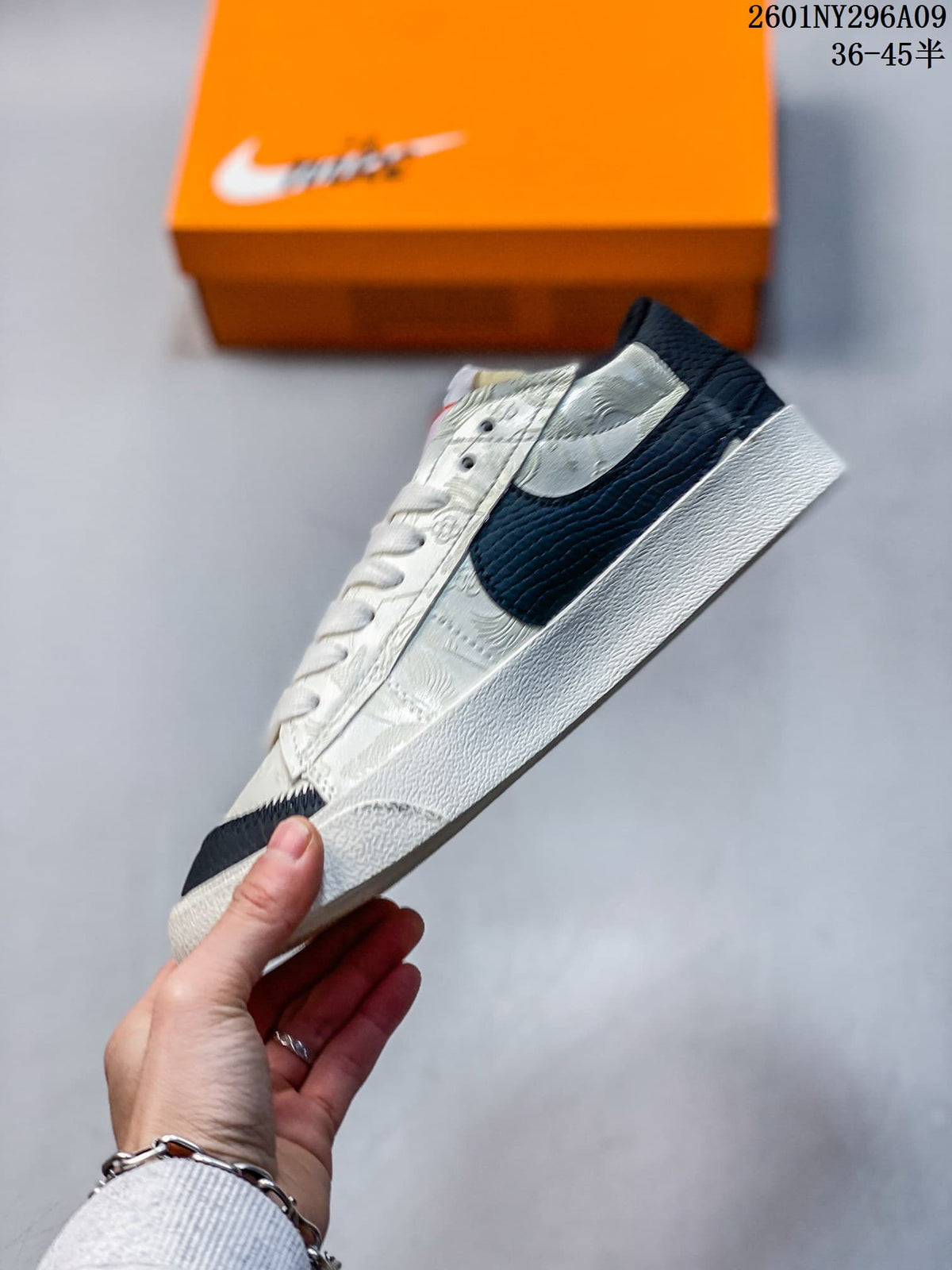 Side profile of the sneaker showing the oversized black Swoosh, white upper with embossed detailing, and white rubber midsole.