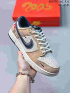 Close angled view showing the tan and white upper, dark textured Swoosh, white laces, and navy outsole accents.