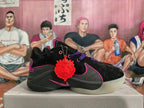 Side view of a black basketball shoe with pink trim, a Nike Swoosh, and a red decorative tag