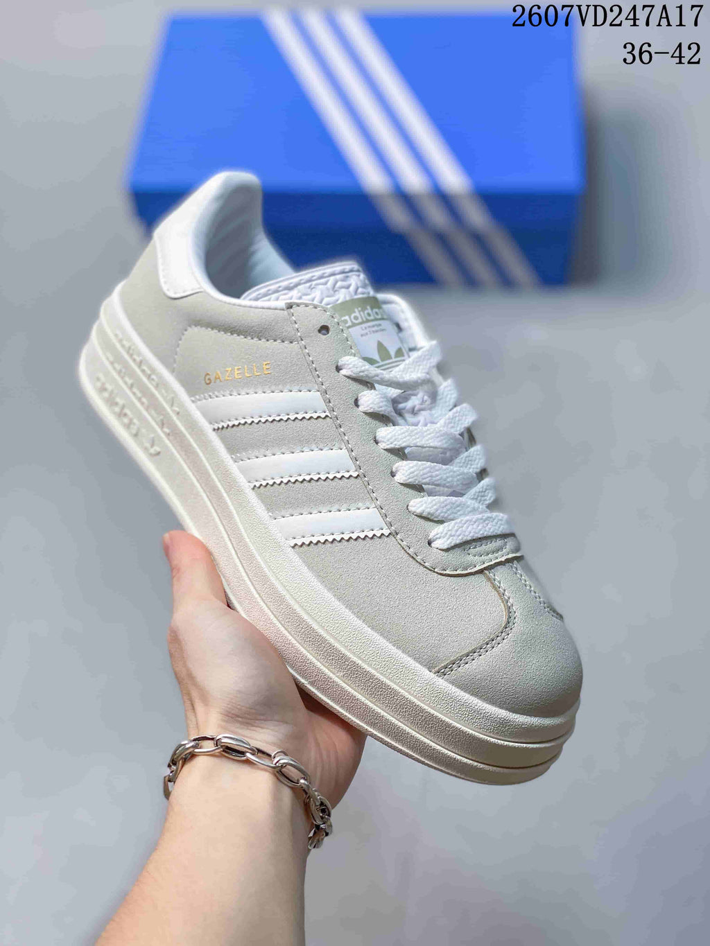 Angled side view of the light gray Gazelle sneaker with visible Gazelle branding, white stripes, and a raised sole.