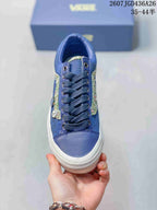 Top view of the blue sneaker showing dark laces, metal eyelets, textured side details, and a white toe bumper.