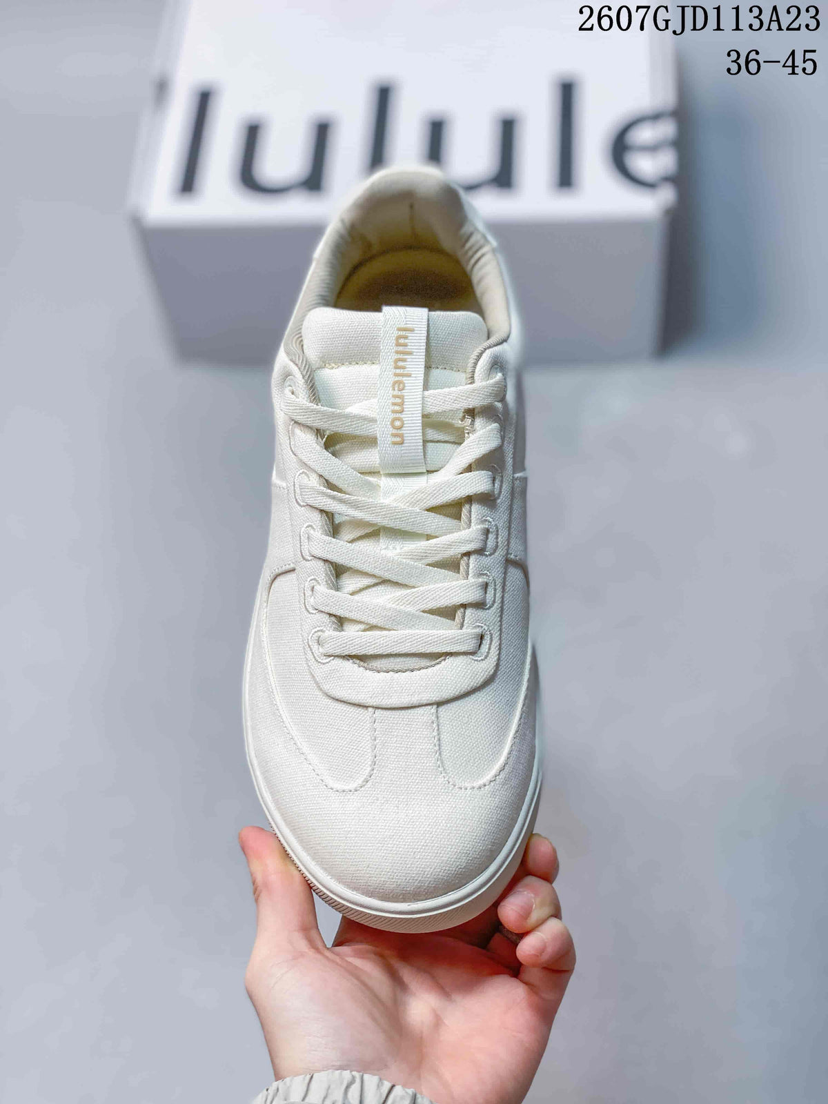 Top view of the white sneaker showing the rounded toe, flat laces, tongue branding, and tonal stitching.