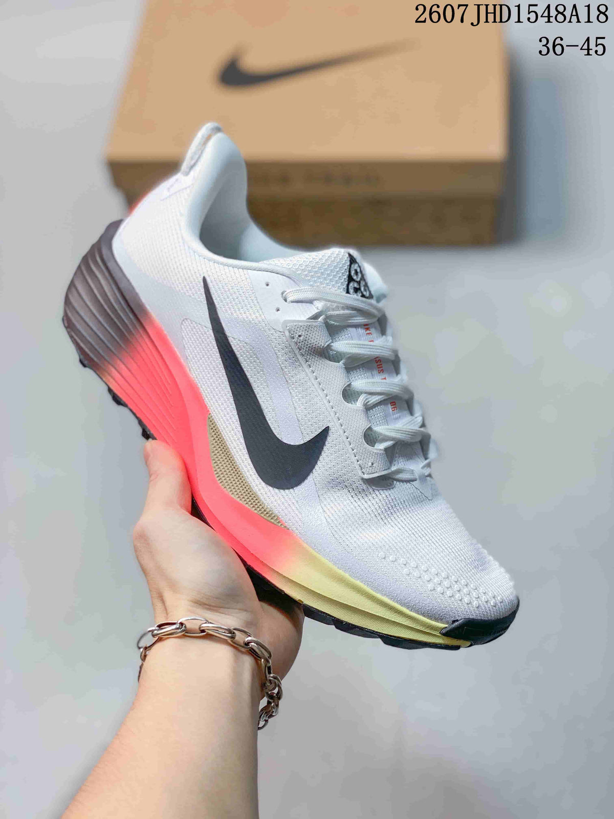 White Nike ReactX Pegasus ACG Trail 6 sneaker with a bright coral and yellow gradient midsole area.