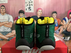 Front view of dark green high-top basketball sneakers with black trim, yellow lining and white toe sections.